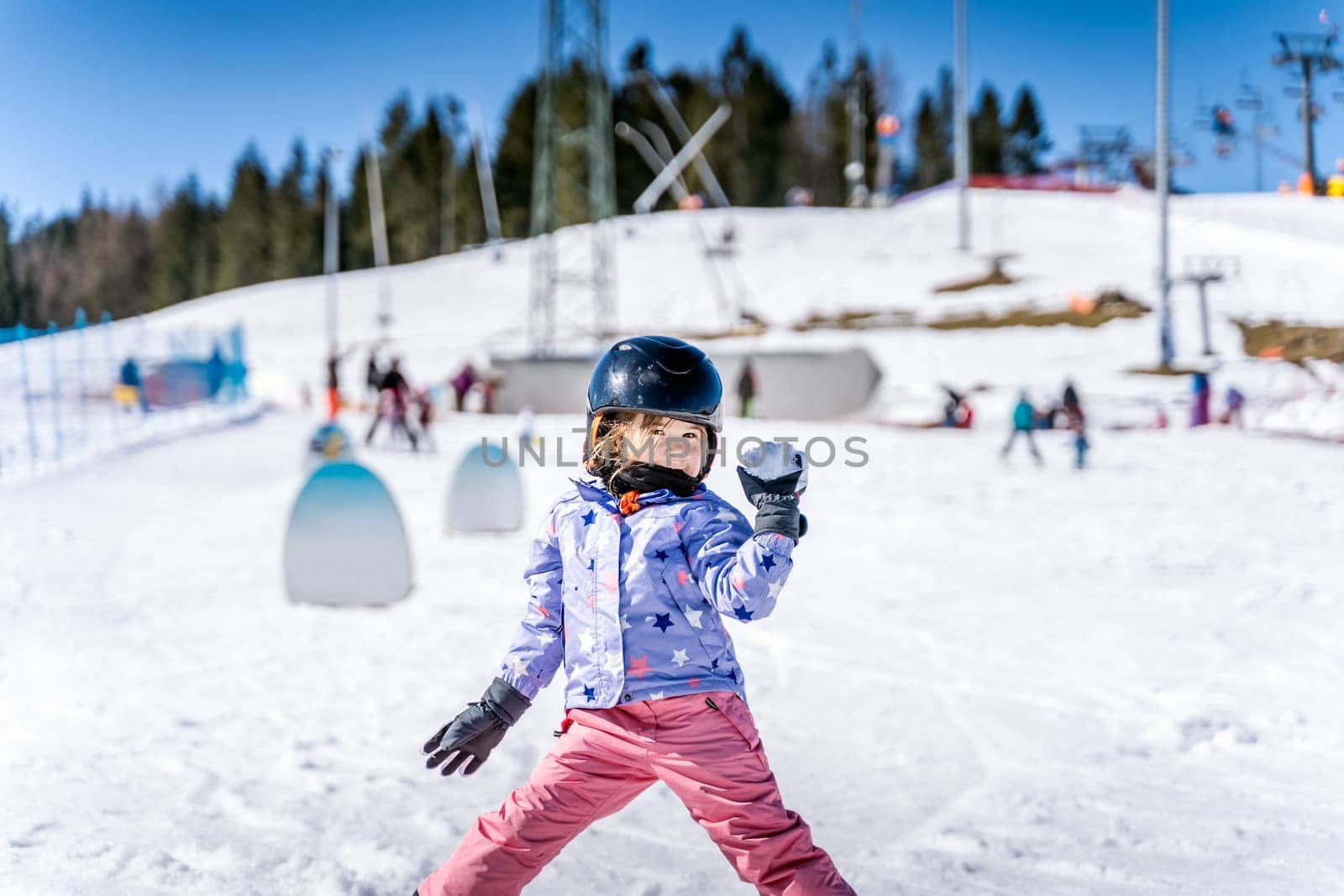 Young happy skier girl throwing snowballs in snowball fight. Young skier having fun on ski slope, Bialka Tatrzanska, Tatry, Poland