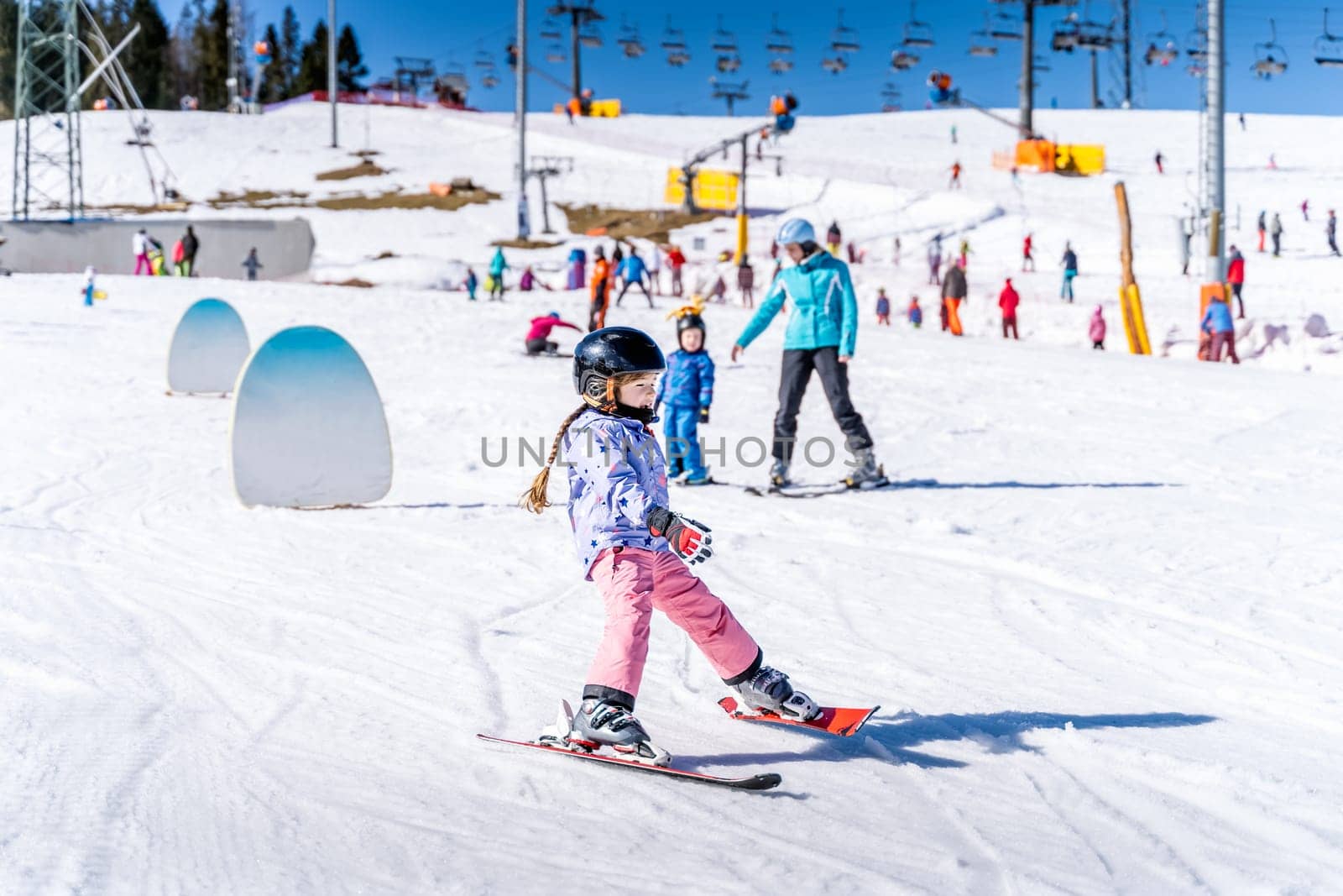 Young happy skier girl learning how to ski on the green ski zone. Young skier having fun on ski slope, Bialka Tatrzanska, Tatry, Poland