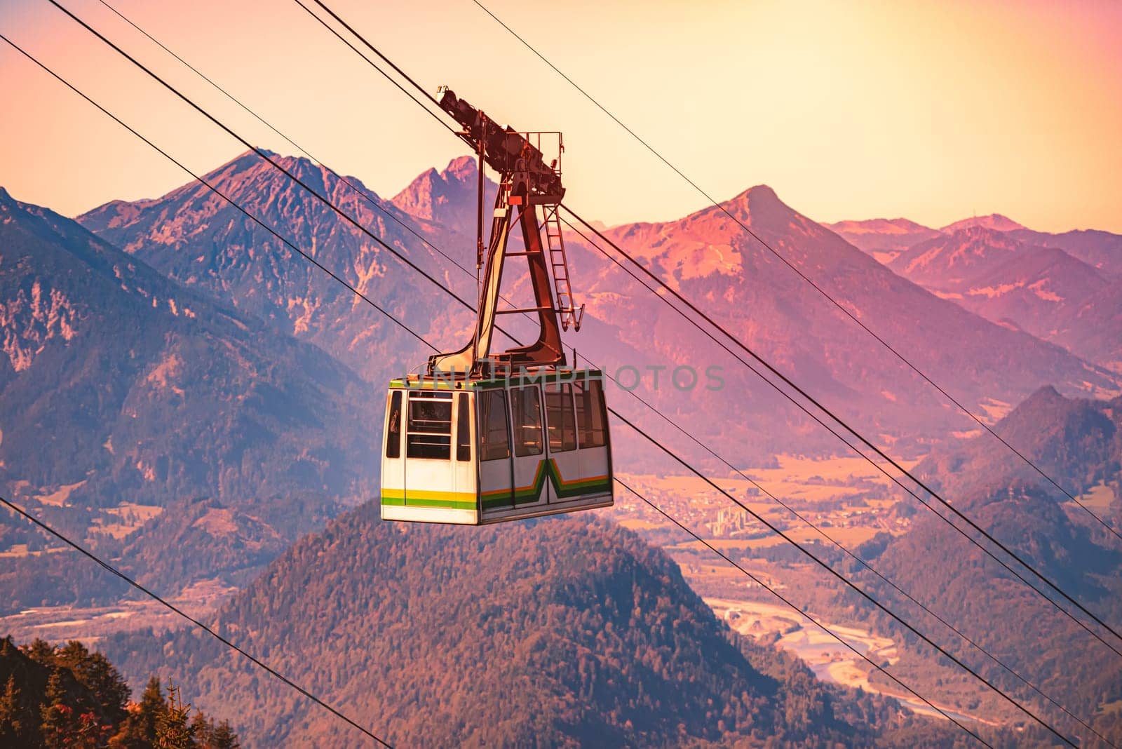 Tegelberg Cable Car in Bavaria, near Fussen, Germany, Europe. Mountain slope in foreground with trees and distant sunset mountains in background