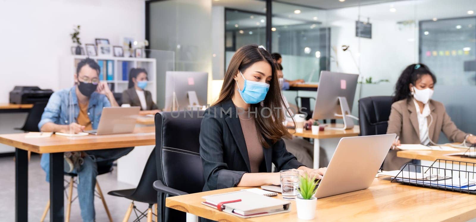 Panoramic group of business worker team wear protective face mask in new normal office with social distance practice with hand sanitiser alcohol gel on table prevent coronavirus COVID-19 spreading
