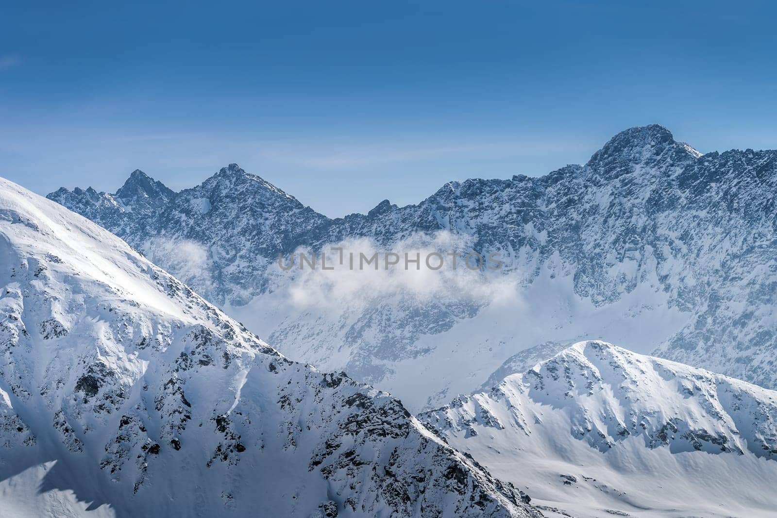 View from Kasprowy Wierch at rocky mountain peak at winter. Amazing mountain range with snow capped mountain peaks in Tatra Mountains, Poland