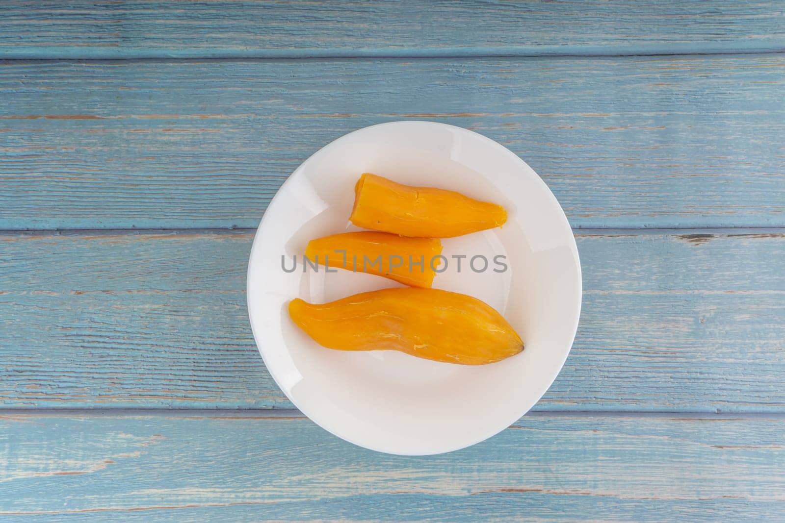 Ubi rebus or steam cassava is traditional malay dish on wooden background. Selective focus