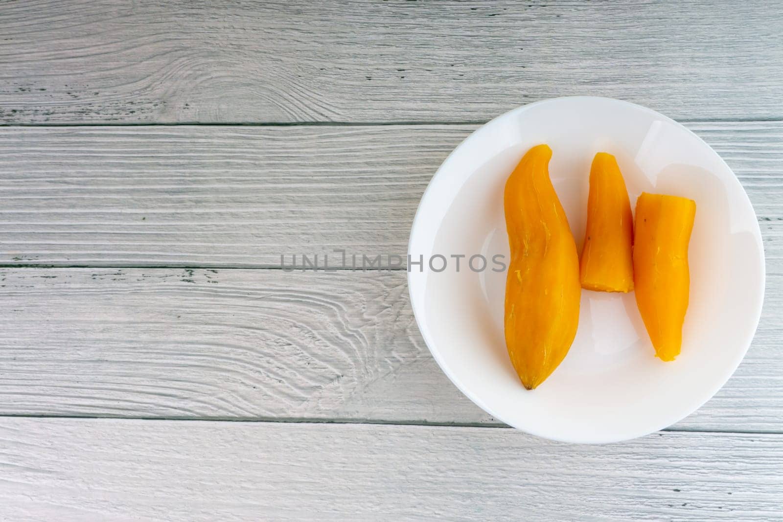 Ubi rebus or steam cassava is traditional malay dish on wooden background. Selective focus