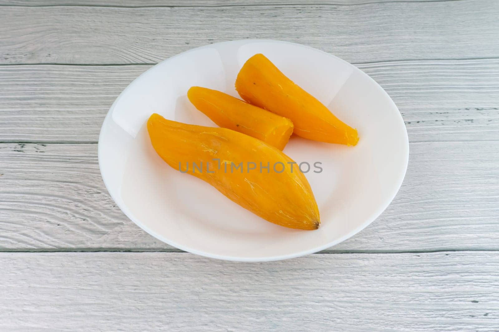 Ubi rebus or steam cassava is traditional malay dish on wooden background. Selective focus