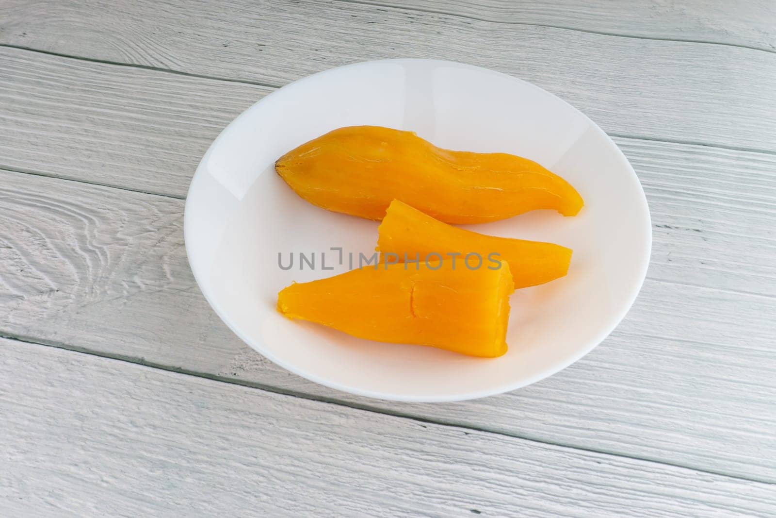 Ubi rebus or steam cassava is traditional malay dish on wooden background. Selective focus