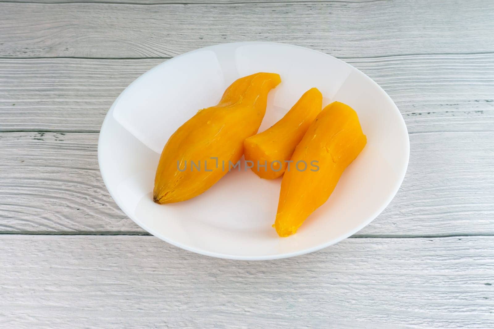 Ubi rebus or steam cassava is traditional malay dish on wooden background. Selective focus