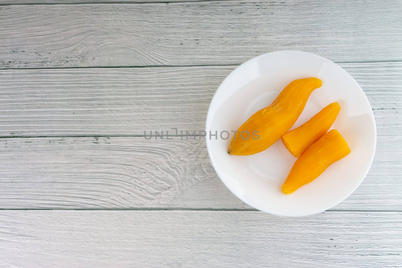 Ubi rebus or steam cassava is traditional malay dish on wooden background. Selective focus