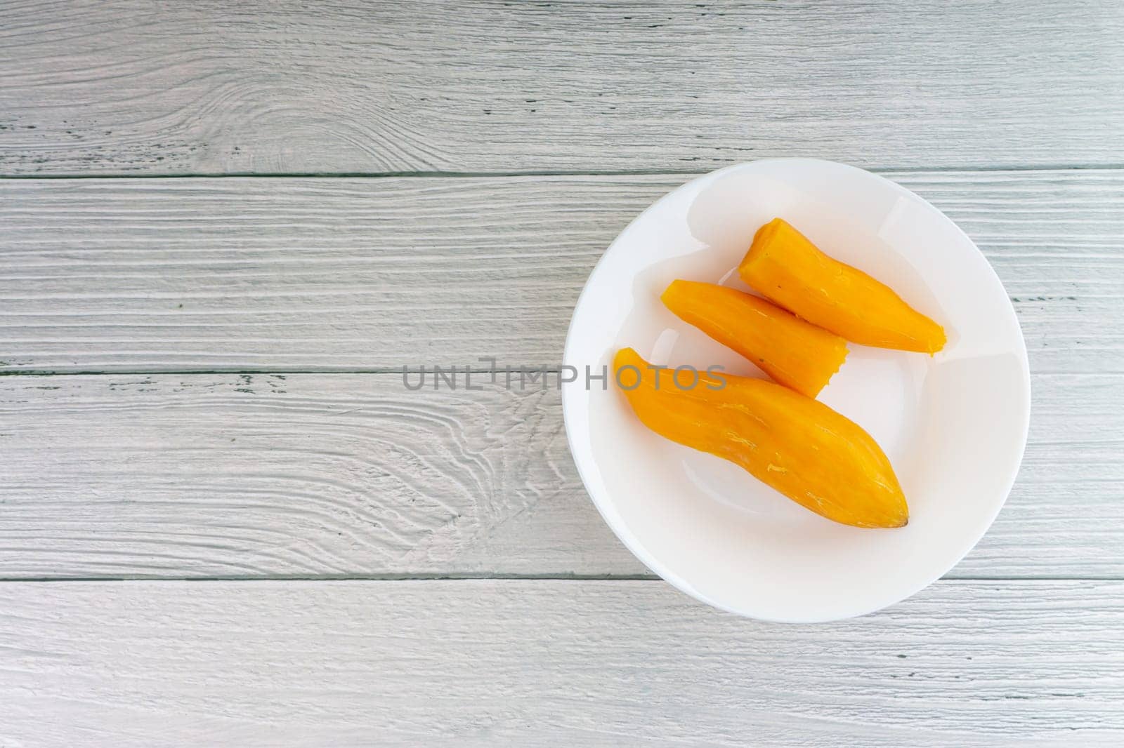 Ubi rebus or steam cassava is traditional malay dish on wooden background. Selective focus