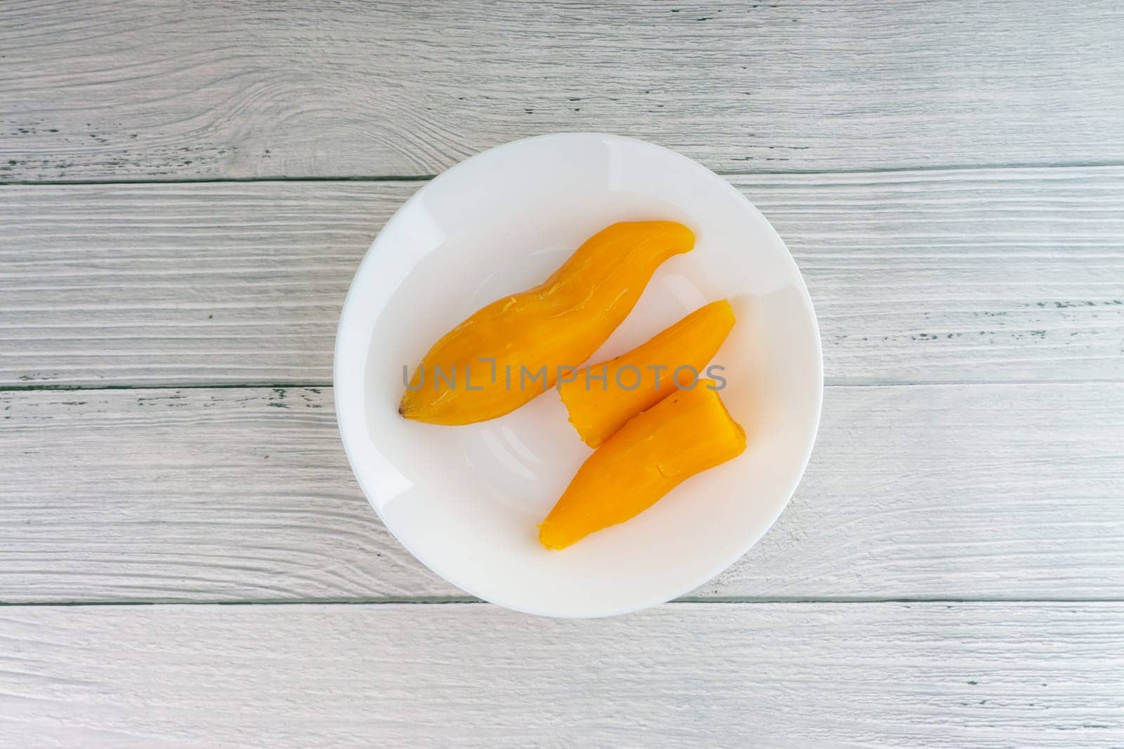 Ubi rebus or steam cassava is traditional malay dish on wooden background. Selective focus