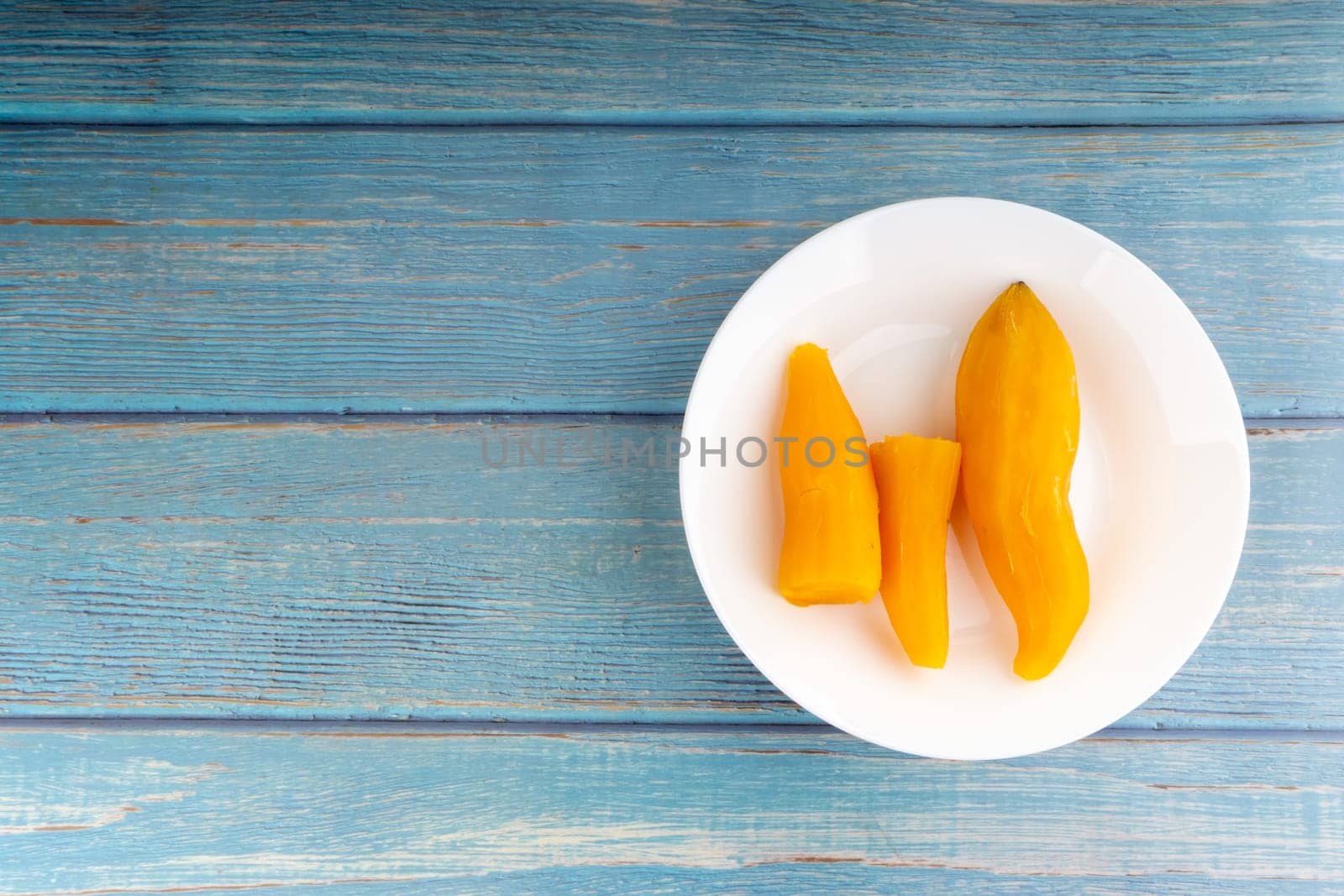 Ubi rebus or steam cassava is traditional malay dish on wooden background. Selective focus