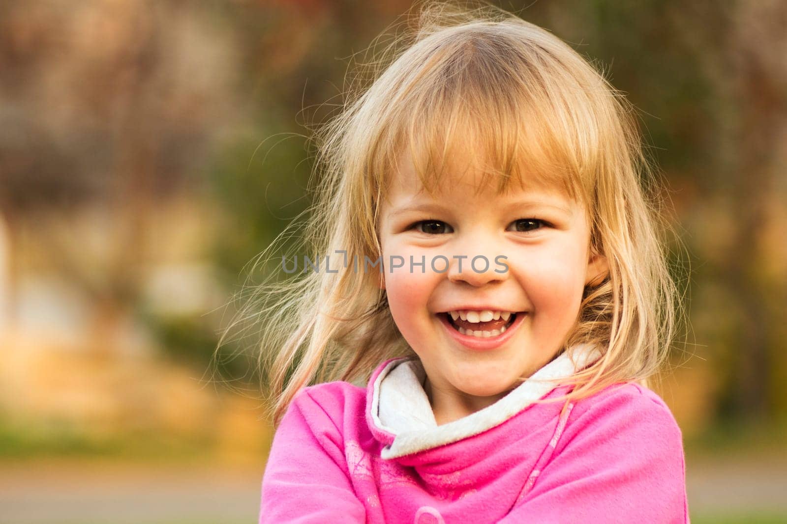 Child portrait of cheerful laughing cute blond hair little girl, happy childhood concept.
