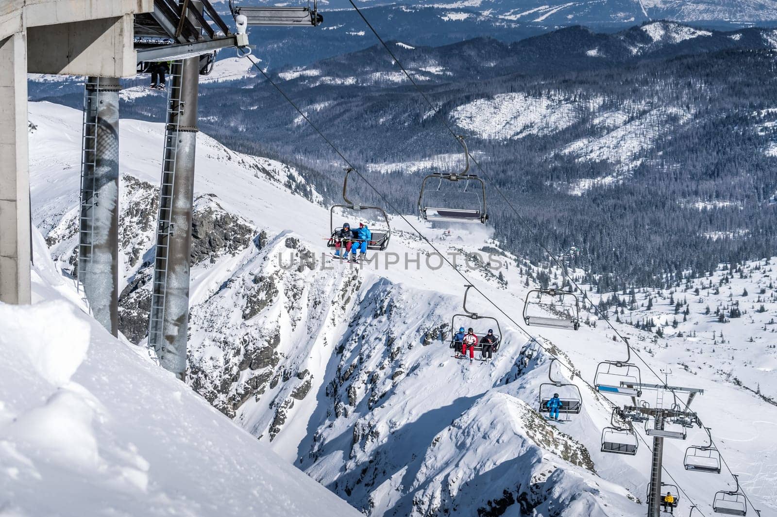 Skiers and snowboarders going up the ski slopes of Kasprowy Wierch on a ski lift. Winter holidays in High Tatra Mountains, Poland