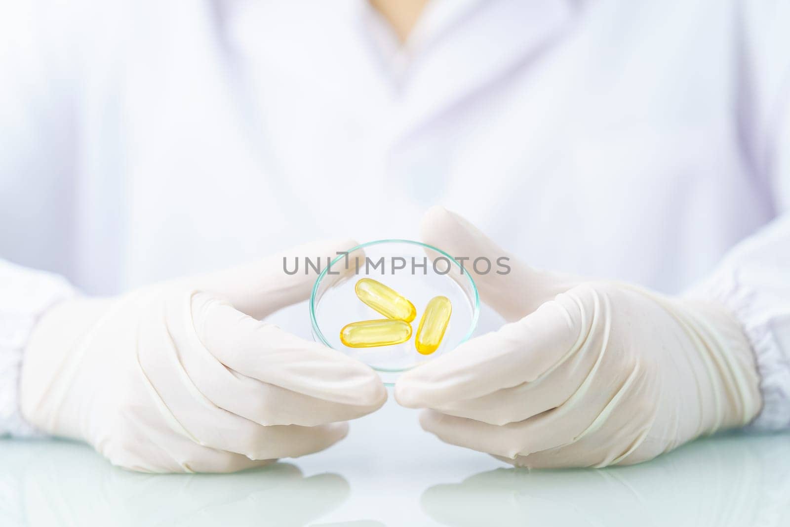 Close up Scientist hands putting in nitrile latex gloves holding Omega 3 capsule in labcoat wearing nitrile gloves, doing experiments in lab
