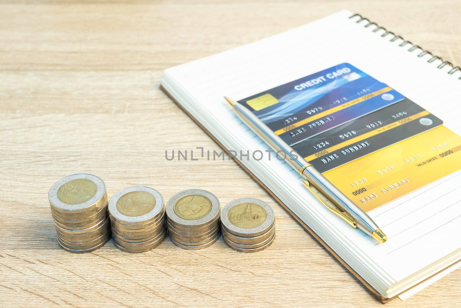 Top view coins with note pad and credit card on wood table using as financial concept