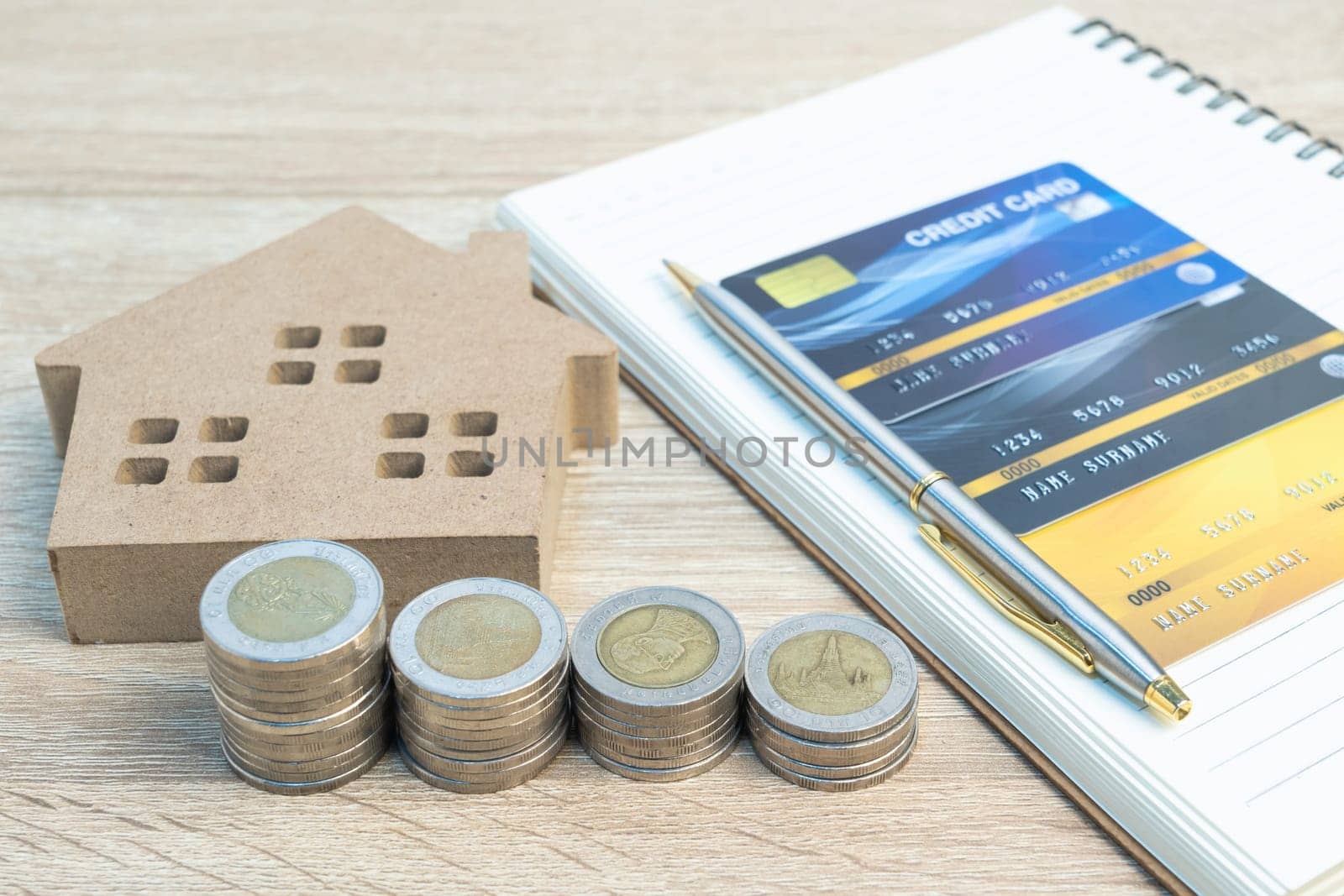 House model and coins with credit card on wood table using as property real estate and financial concept