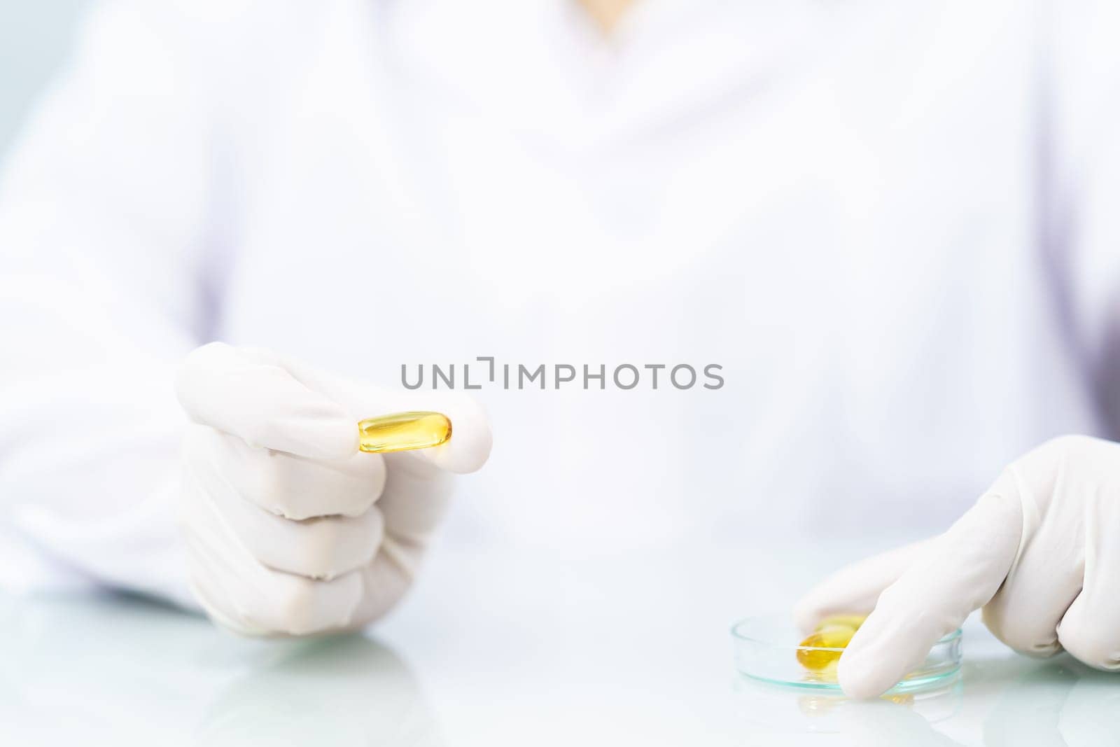 Close up Scientist hands putting in nitrile latex gloves holding Omega 3 capsule in labcoat doing experiments in lab