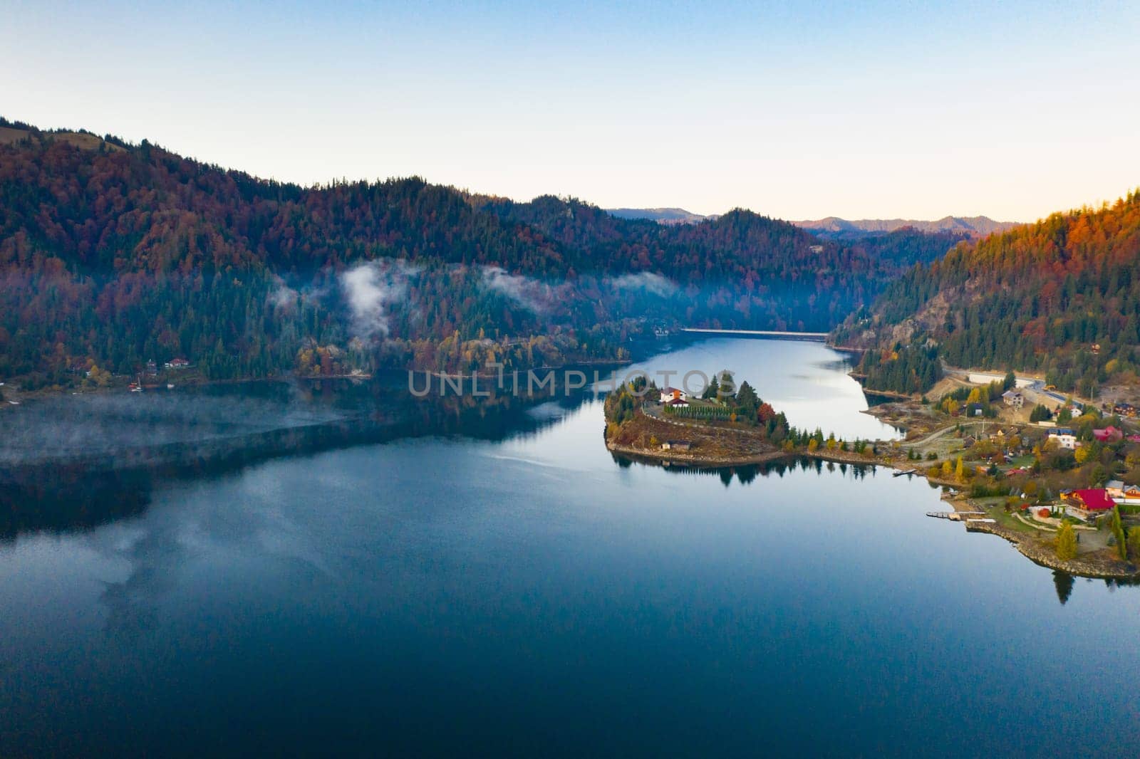 Magic foggy sunrise over Colibita lake at autumn, Romania.