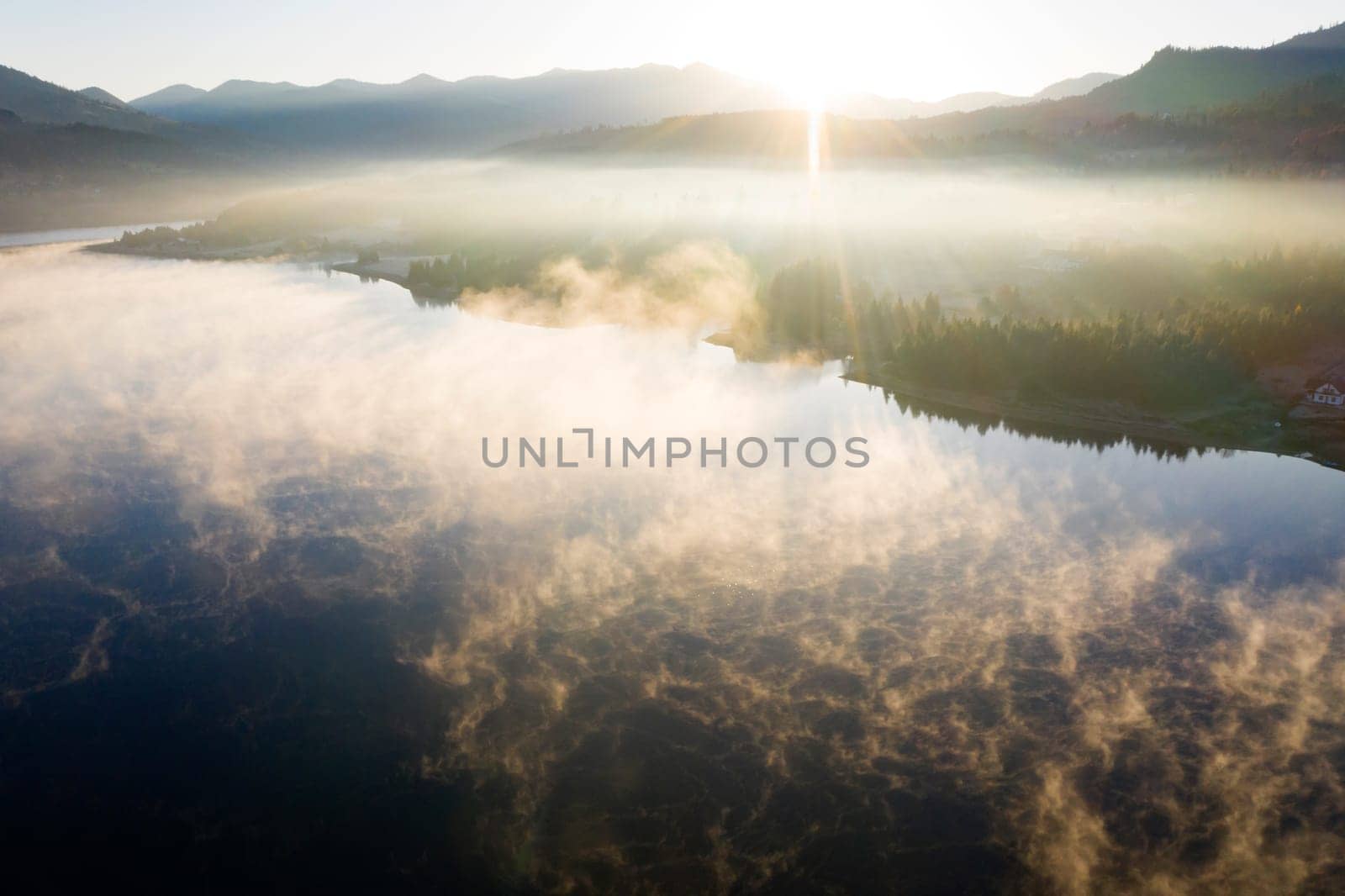 Magic foggy sunrise over Colibita lake at autumn, Romania.
