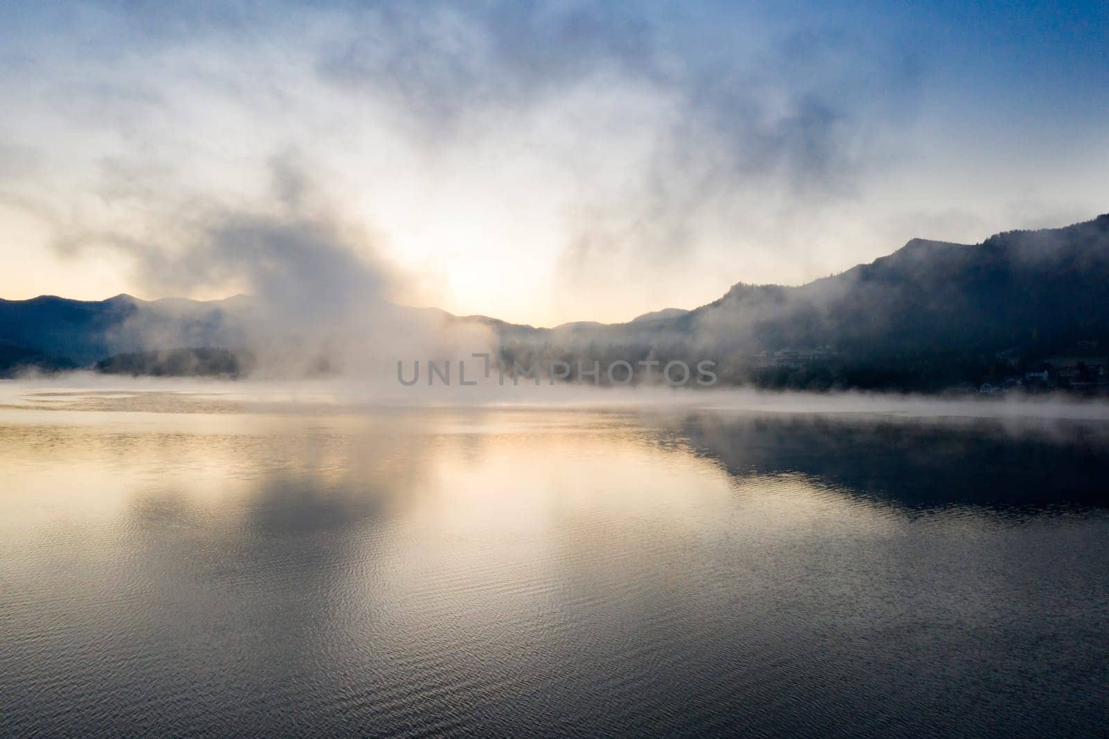 Magic foggy sunrise over Colibita lake at autumn, Romania.