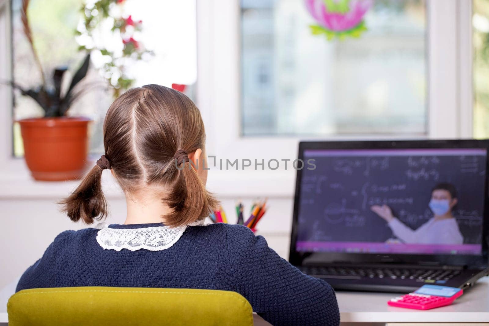 Distance learning-online education. School girl watching online education classes and doing school homework. COVID-19 pandemic forces children online learning.
