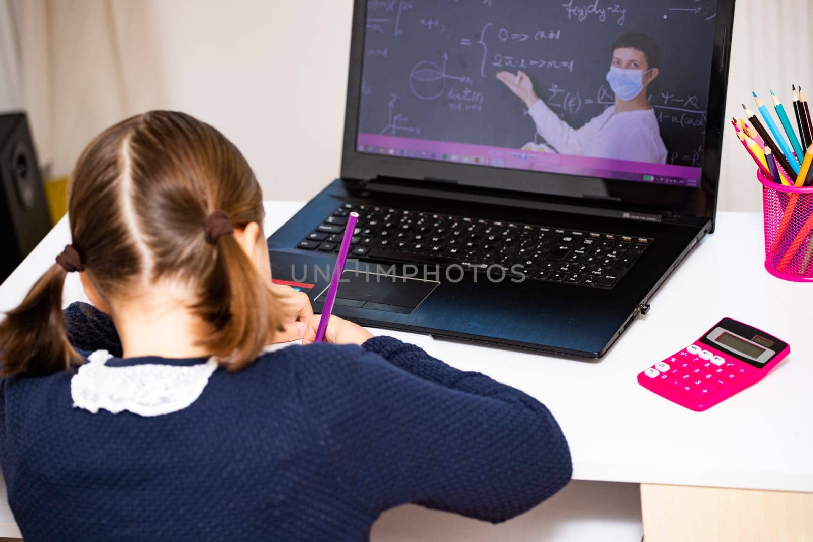 Distance learning-online education. School girl watching online education classes and doing school homework. COVID-19 pandemic forces children online learning.
