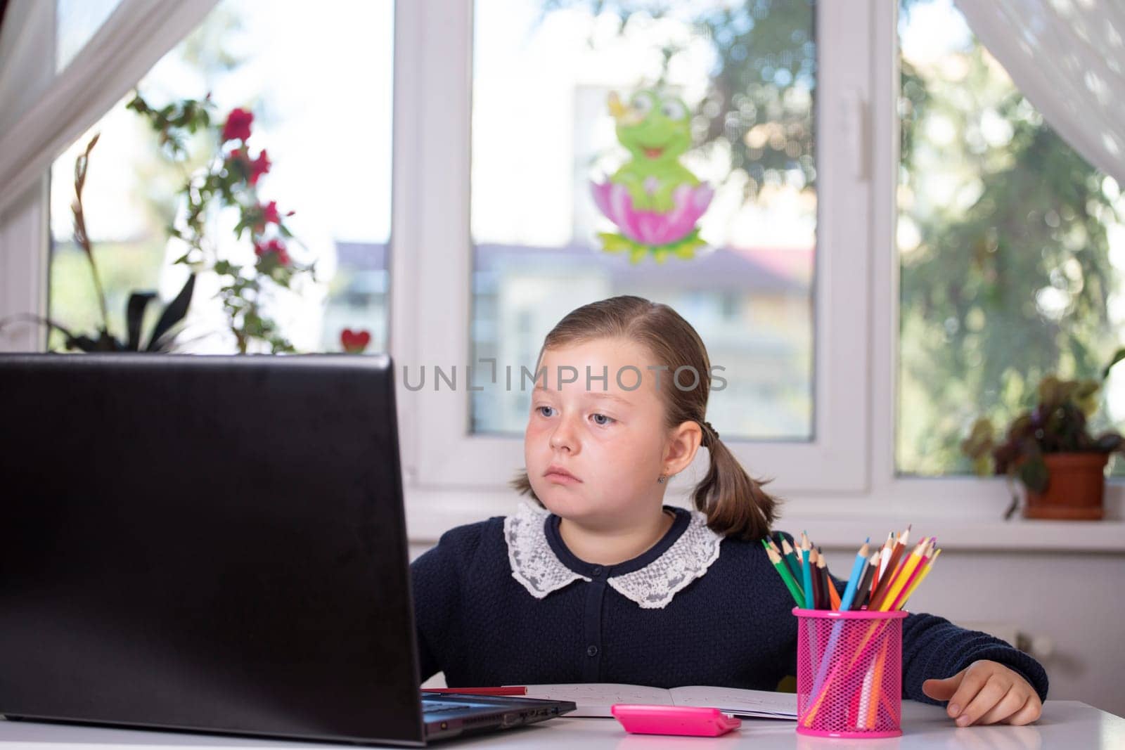 Distance learning-online education. School girl watching online education classes and doing school homework. COVID-19 pandemic forces children online learning.