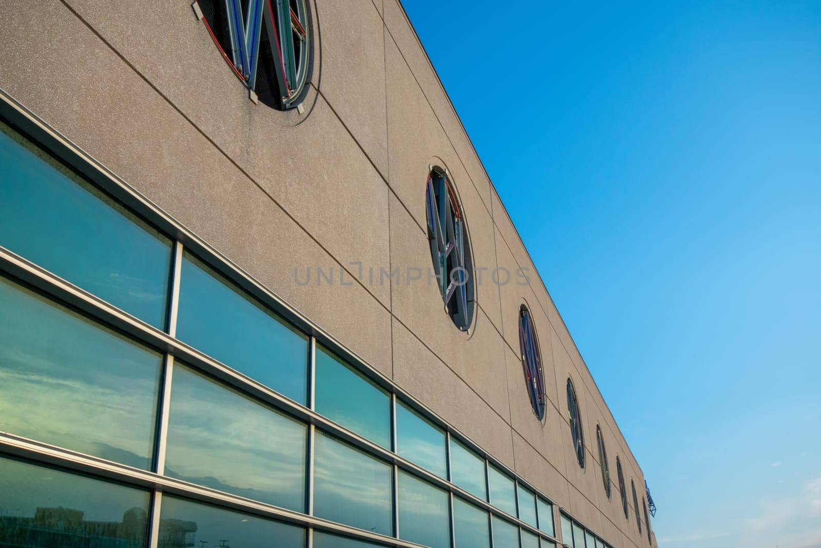 A Tan Building With a Large Window Reflecting the Sunset Sky
