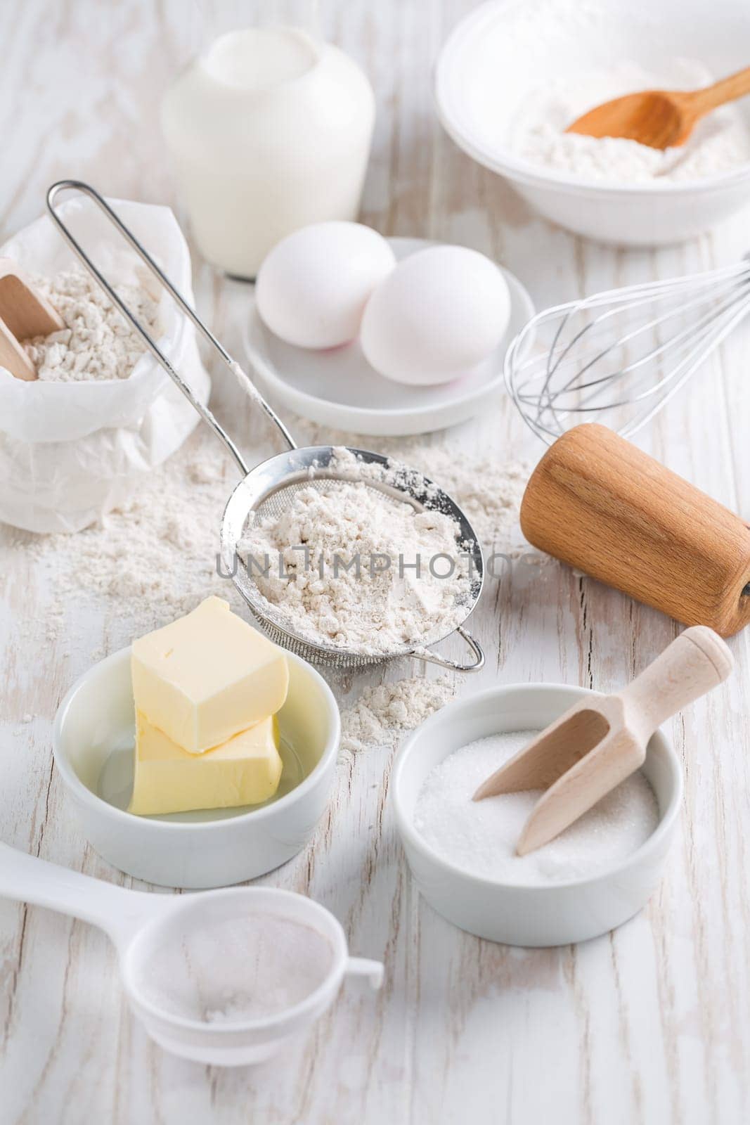 Spelt flour, sugar with baking ingredients and kitchen utensils on white wooden table.