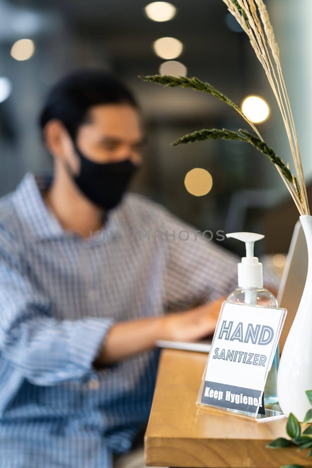 Signage of Hand Sanitizer around office for hygiene practice after reopen with blurred background of business people working and wear face mask in new normal office to prevent covid-19 virus spreading