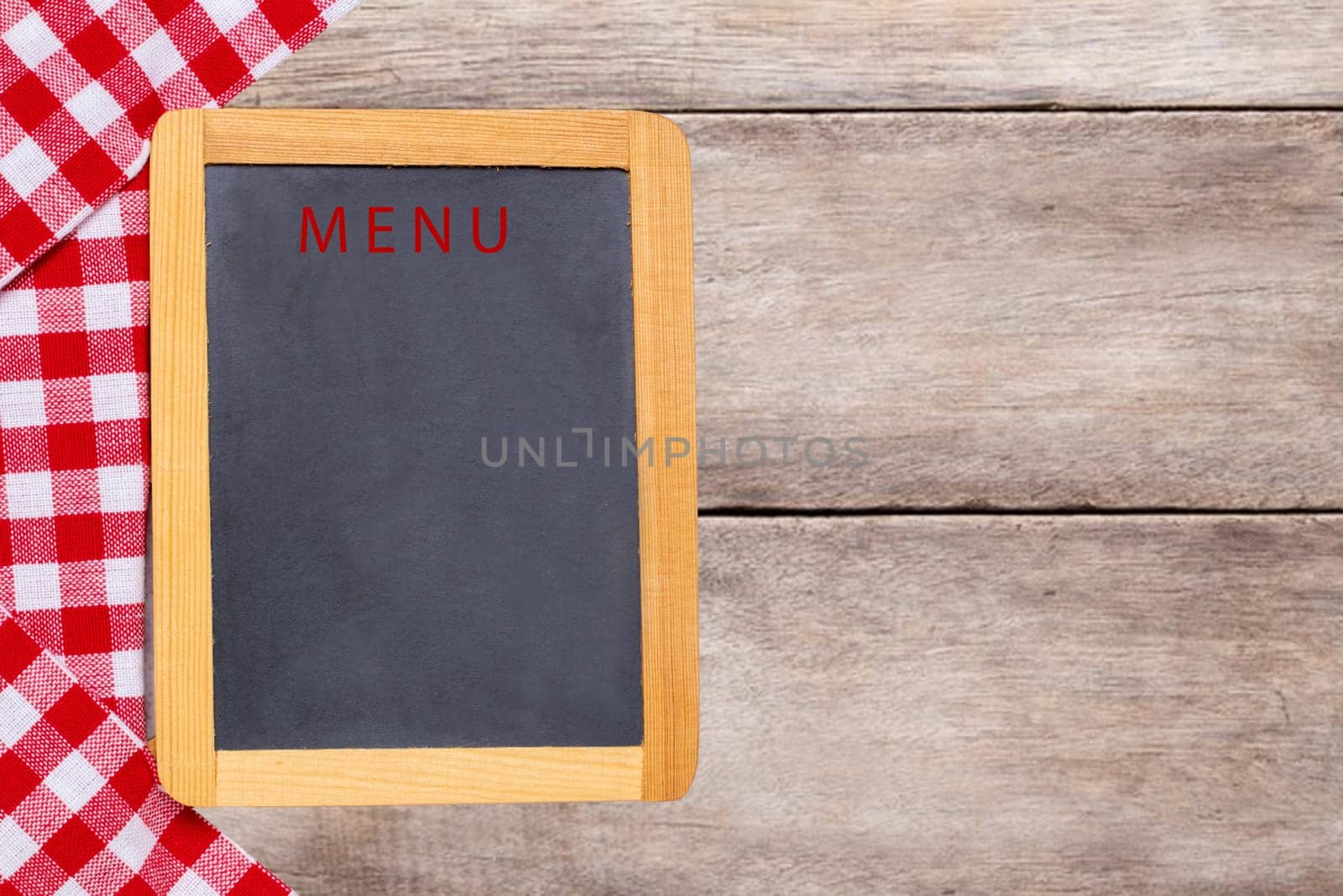 Food recipe template. Empty wooden black board and a red white checkered cloth on rustic bright table. For your food and product display montage. Copy space.