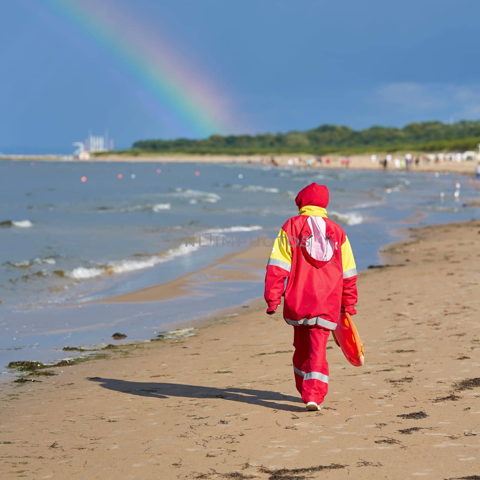 Lifeguard on the beach on the Polish Baltic coast near Swinoujscie goes home. In the background a rainbow.