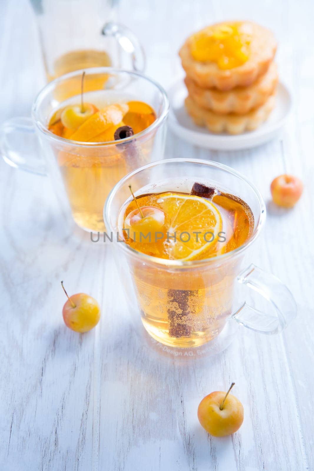 Apple cider cocktail with cinnamon and small lemon curd tarts Mulled apple wine for Christmas.