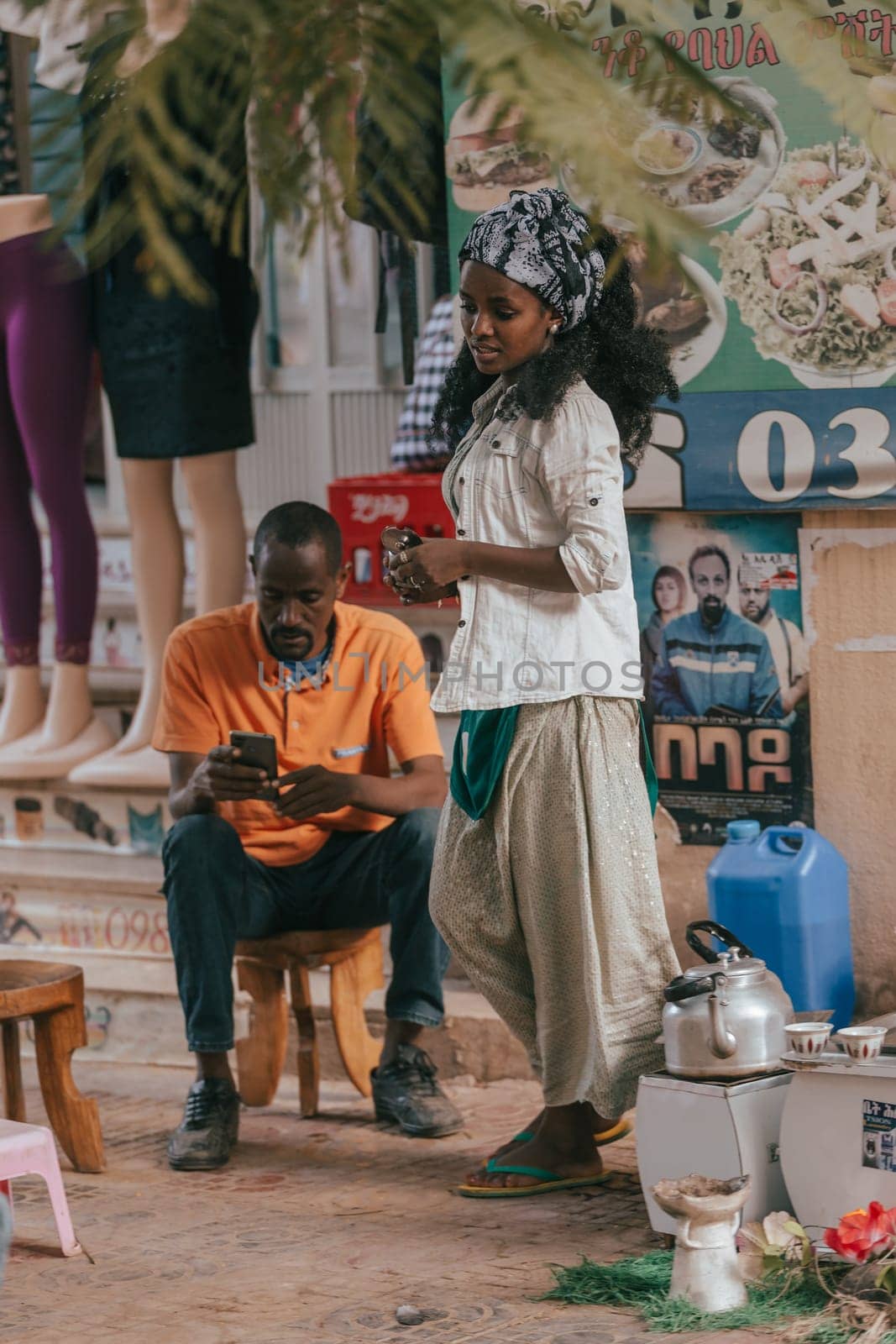 Aksum, Ethiopia - April 27, 2019: Ethiopian traditional Coffee maker, local women preparing bunna cafe behind Aksum KIdist Maryam Hospital, Ethiopia, Africa