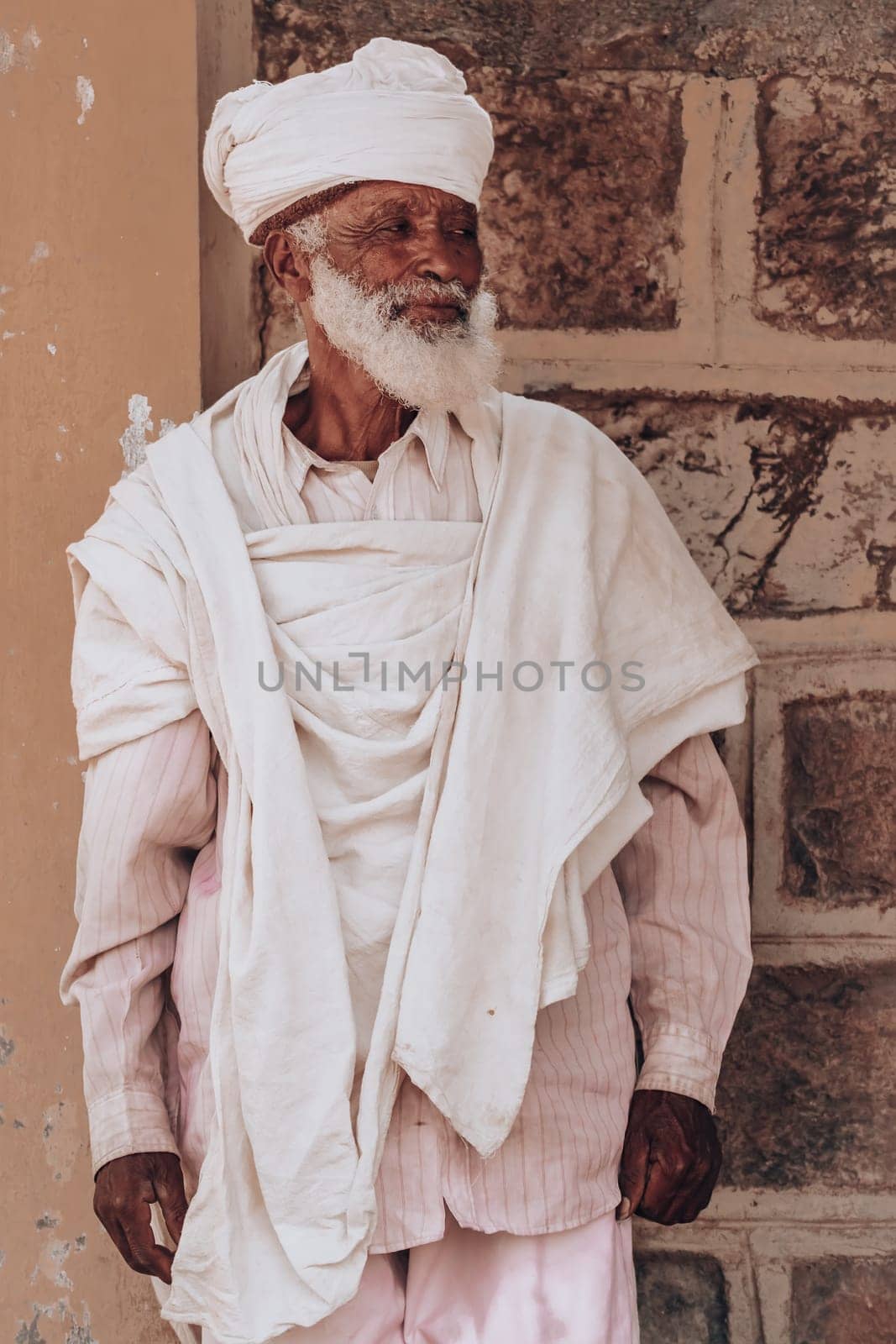 YEHA, ETHIOPIA, APRIL 28th.2019: Old man, orthodox monk or priest behind Yeha Great Temple of the Moon, Aril 28, 2019 in Yeha, Ethiopia Africa