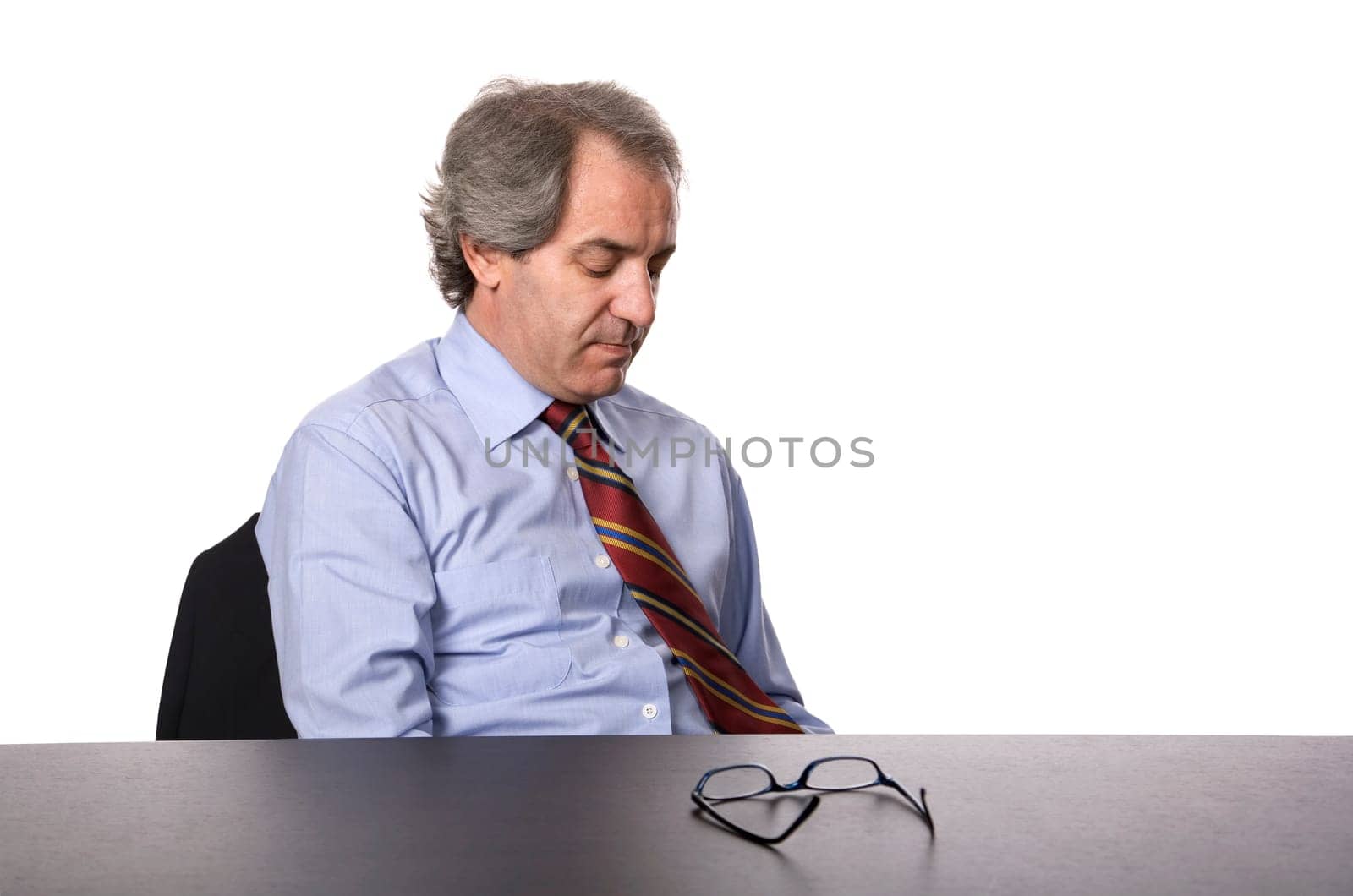 sad mature business man on a desk, isolated on white