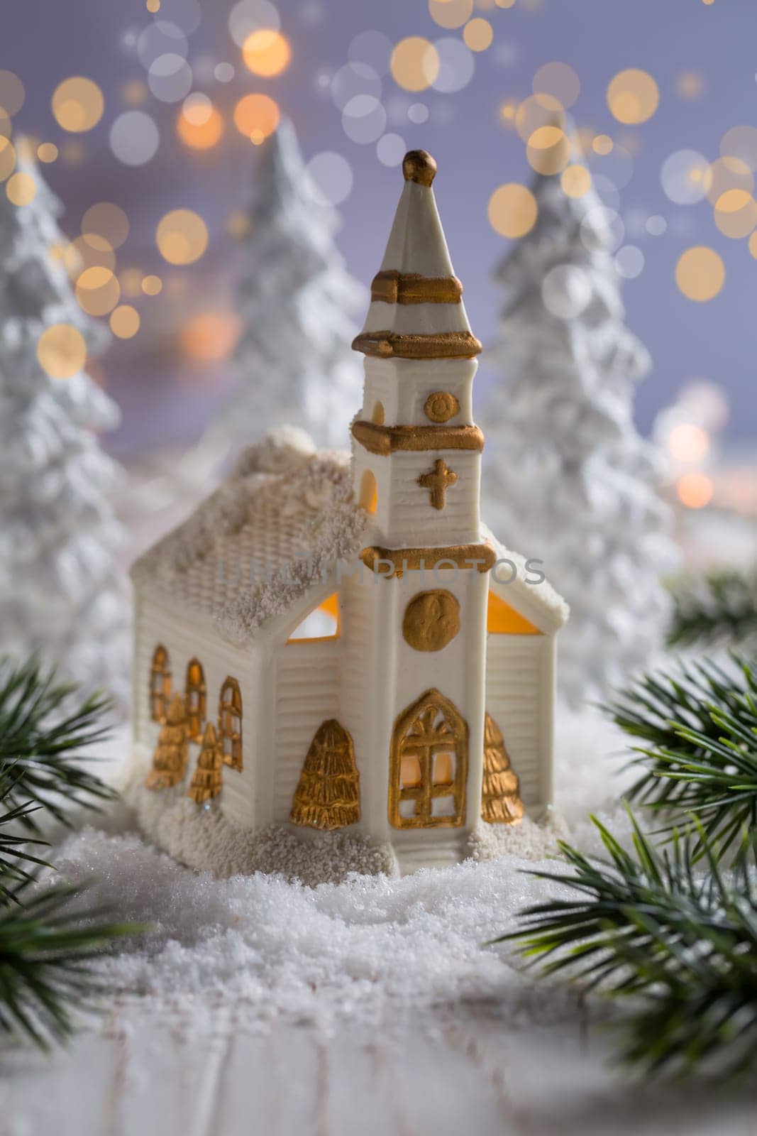 Small church with candles and white trees as snowy landscape. Christmas decoration. Symbol of Christianity.