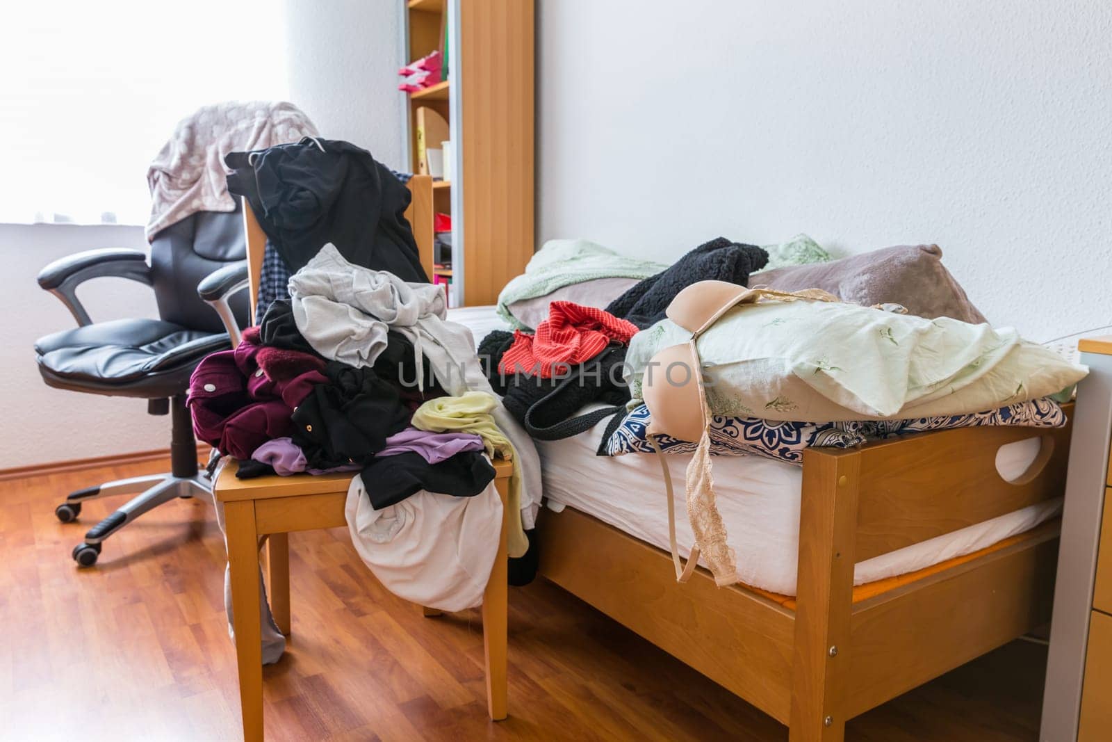 Messy teenager room. Untidy cluttered bed, dirty clothes. Compulsive Hoarding Syndrom.