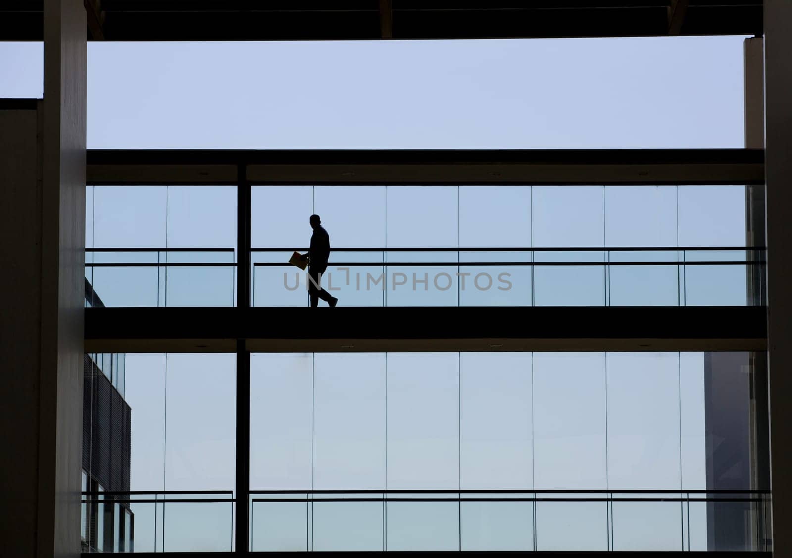Silhouette view of a businessman in a modern office building interior with panoramic windows.
