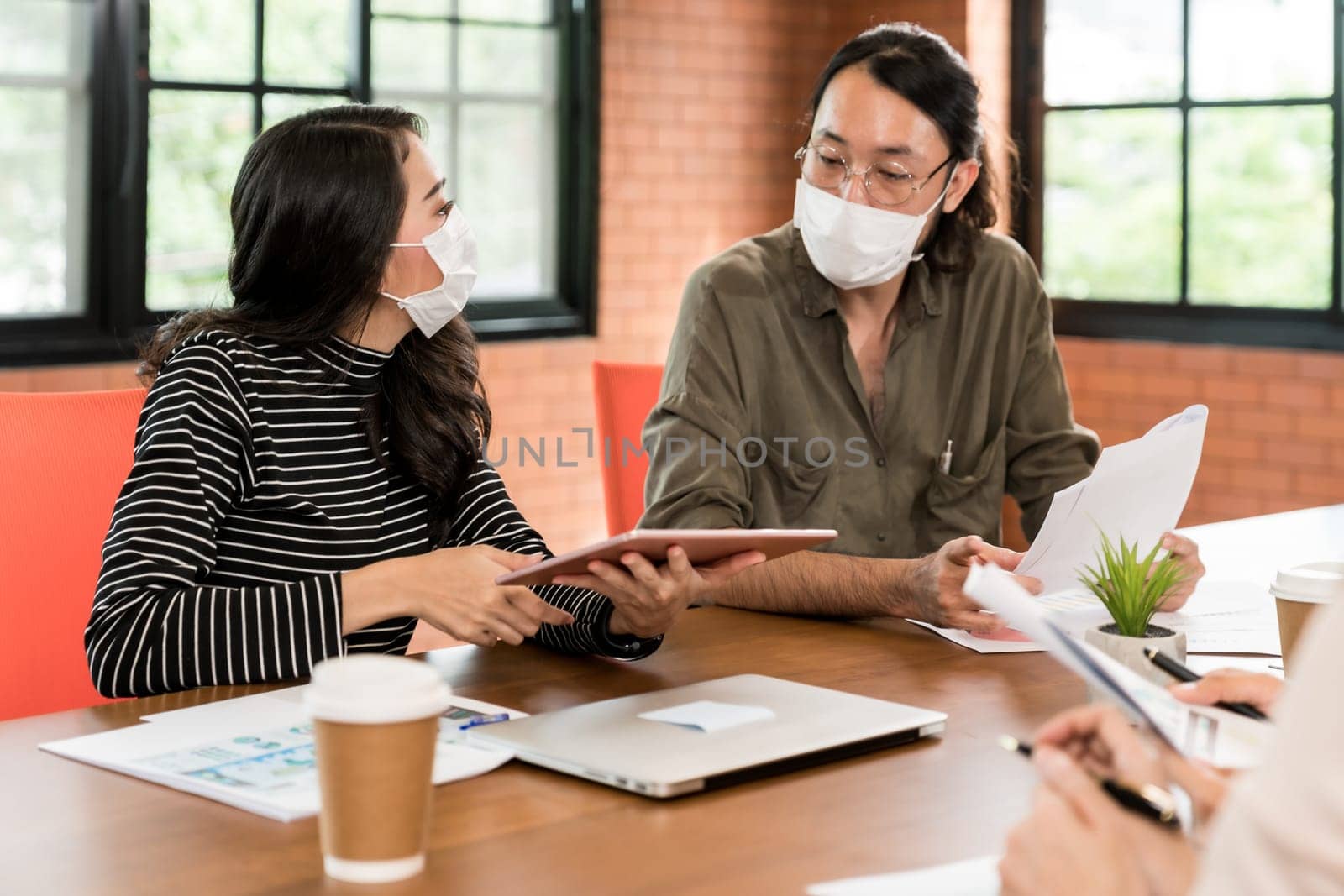 Group of asian business person team meeting and brainstorm in meeting room after office reopen, they wear protective face mask as new normal practice to prevent coronavirus infection.