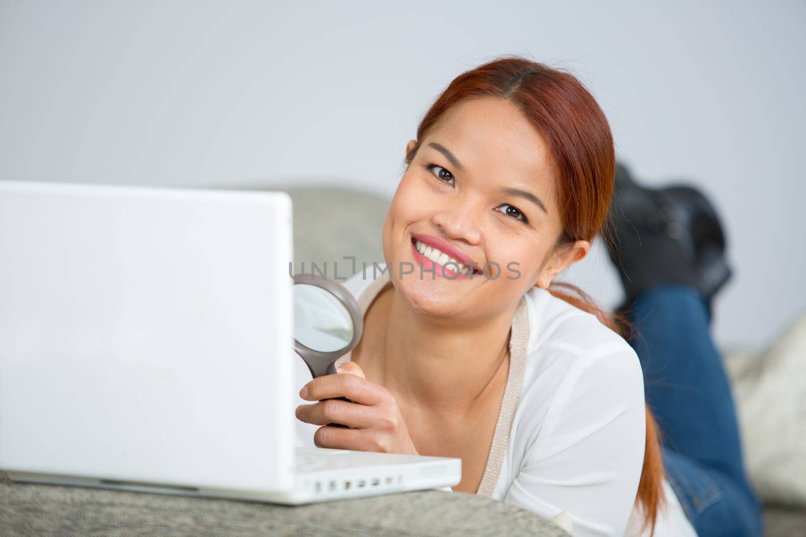young beautiful woman sitting on sofa with laptop at home