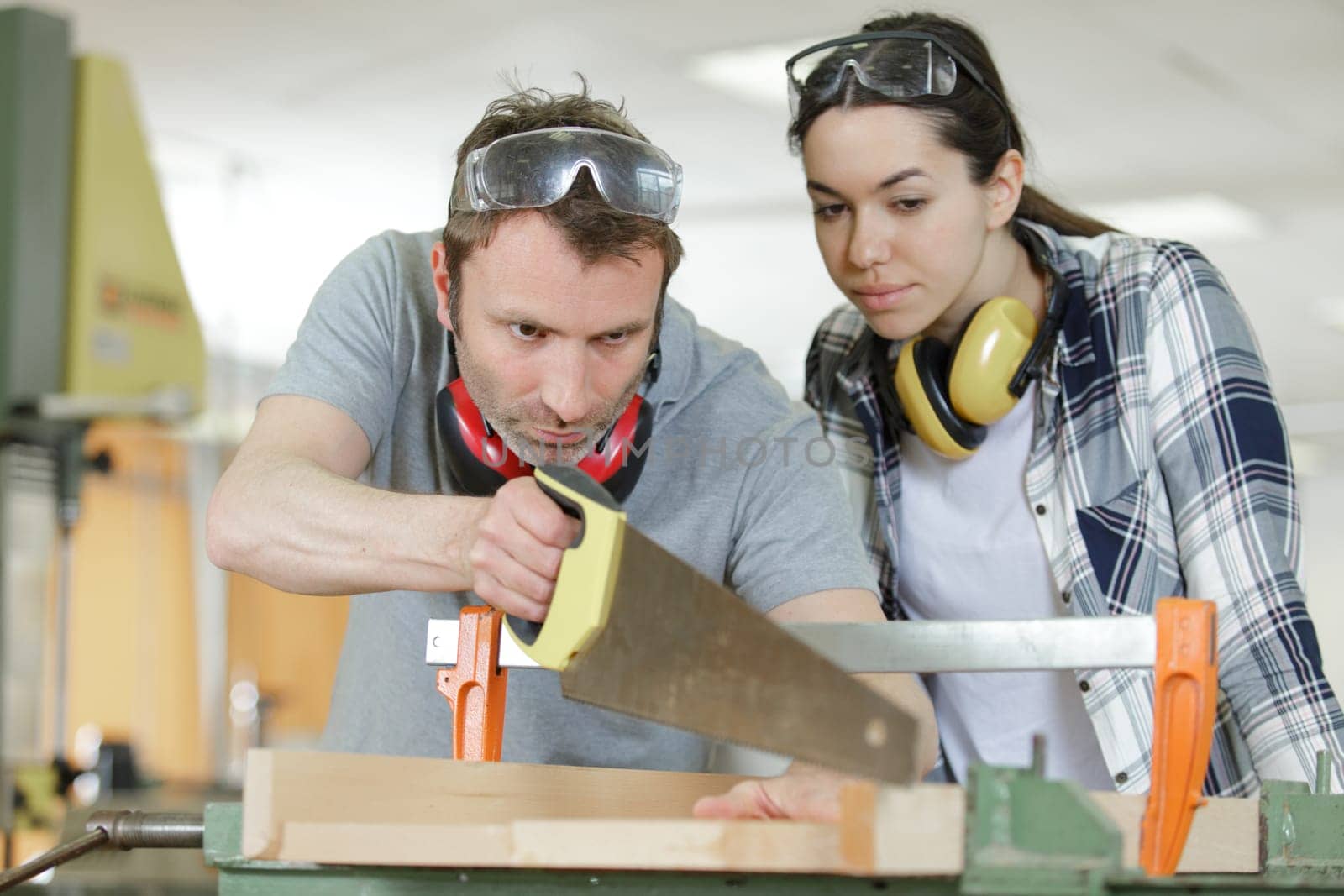 carpenter and apprentice working together in wood workshop