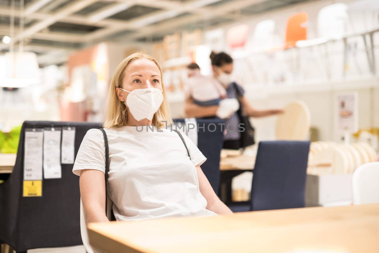 New normal during covid epidemic. Caucasian woman shopping at retail furniture and home accessories store wearing protective medical face mask to prevent spreading of corona virus.