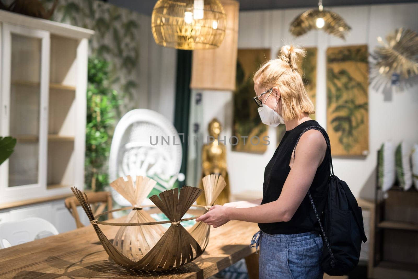 New normal during covid epidemic. Caucasian woman shopping at retail furniture and home accessories store wearing protective medical face mask to prevent spreading of corona virus.
