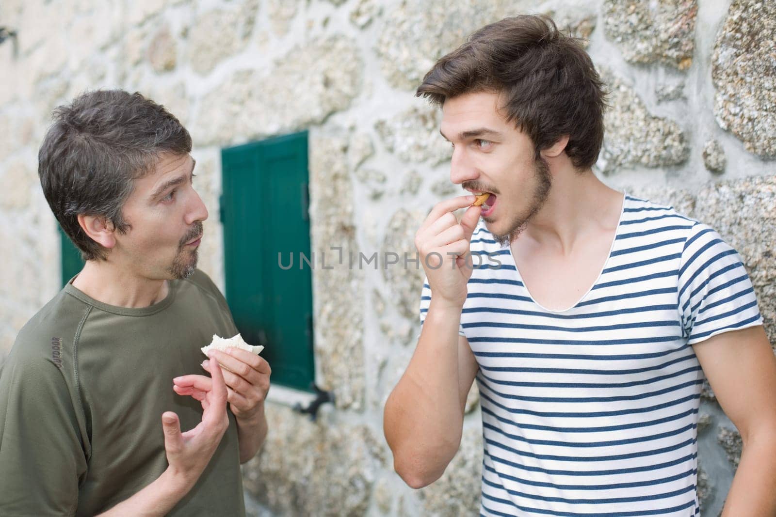 two friends having a snack and talking outdoors