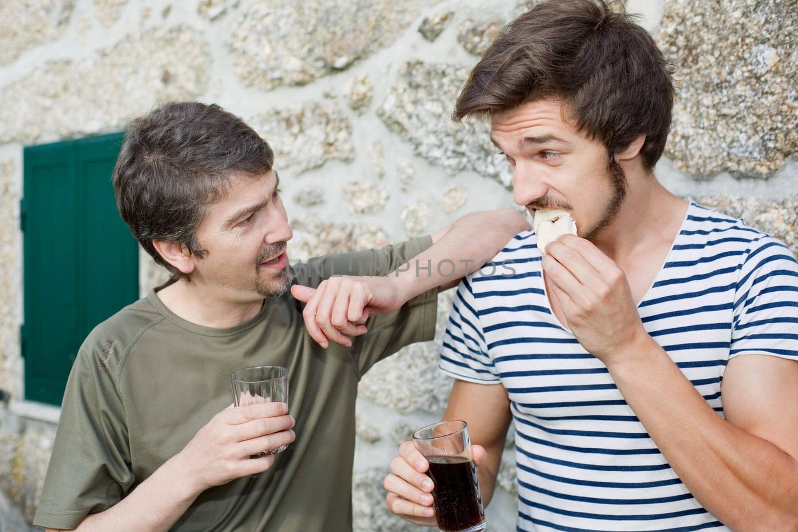 two friends having a drink and talking outdoors