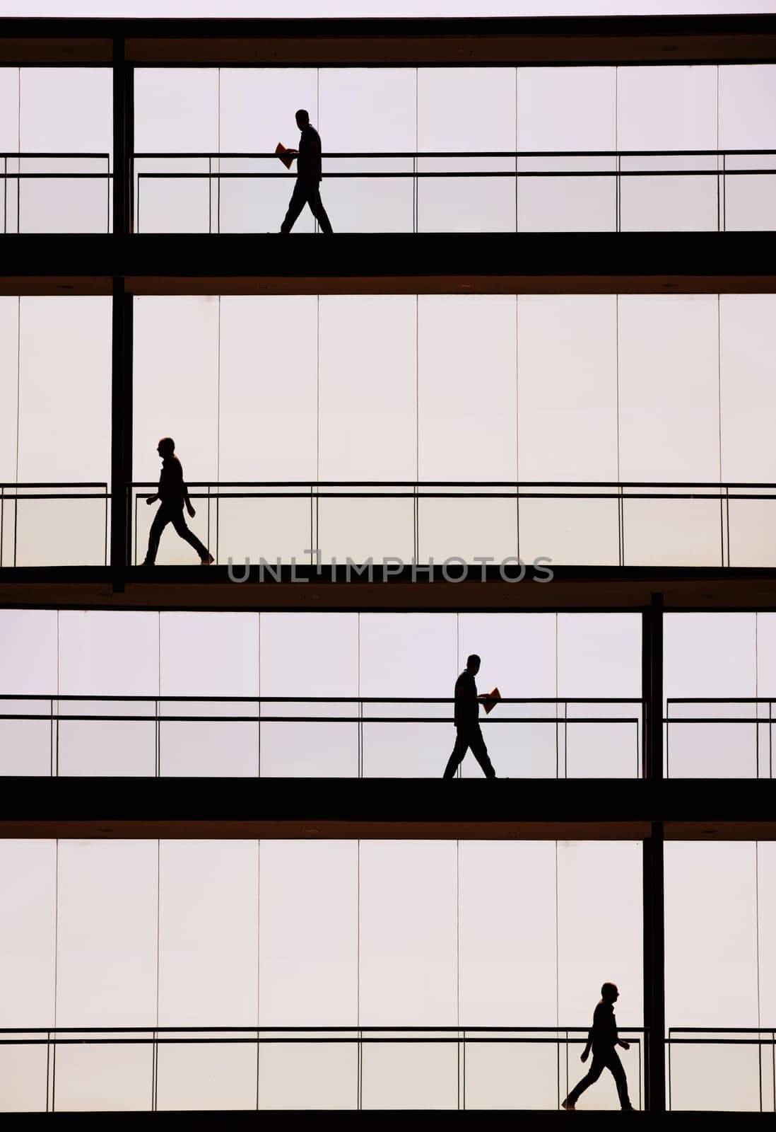 Silhouette view of businessmen in a modern office building interior with panoramic windows.