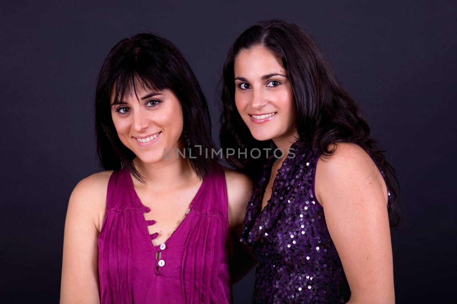 two happy young casual women on a black background