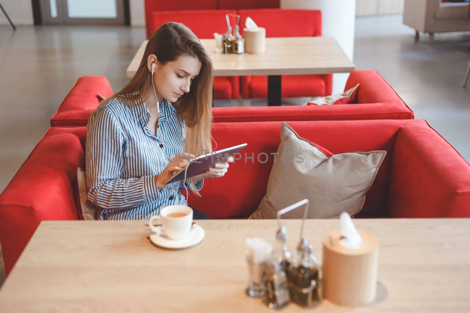 Candid image of a young woman using tablet computer in a cafe