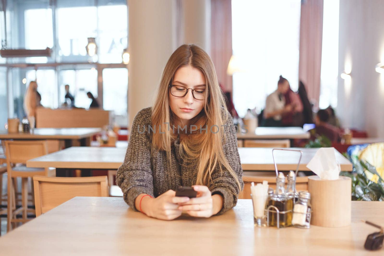 Charming woman with beautiful smile reading good news on mobile phone during rest in coffee shop