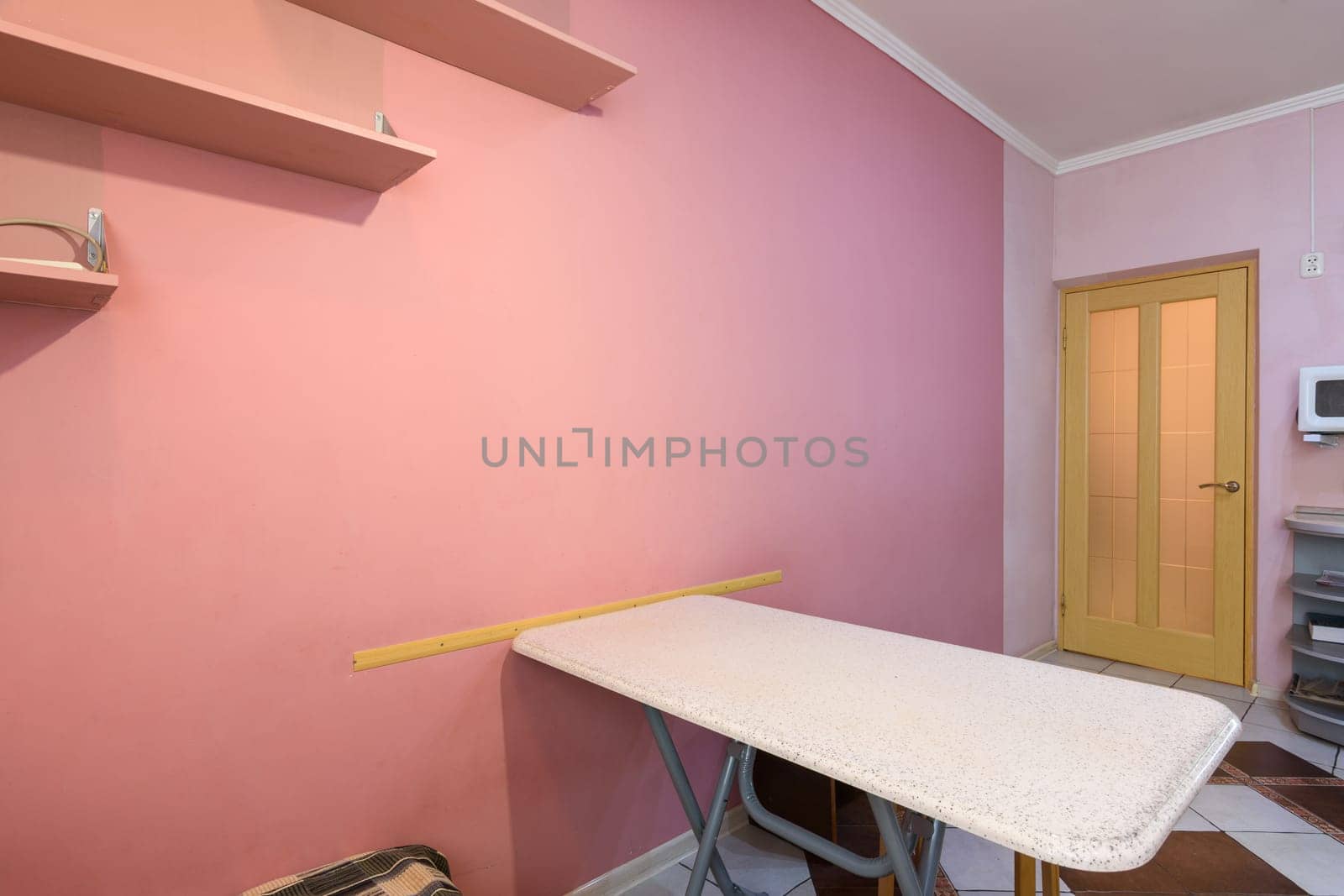 Fragment of kitchen interior, dining table and part of a painted wall with shelves